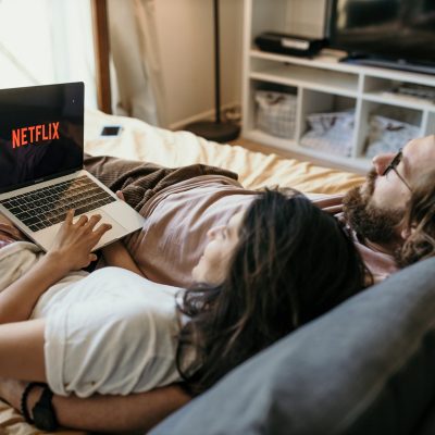 a couple lying in bed watching netflix