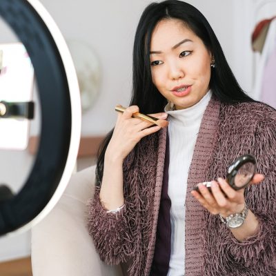 vlogger applying makeup and live streaming with her phone